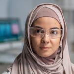 Face of young pretty Muslim female clinician in hijab and protective eyewear