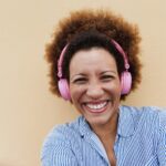 Senior african woman listening music with headphones - Focus on face